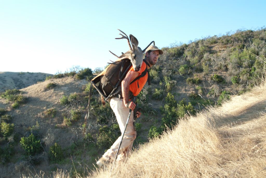 Former Conservancy Plant Conservation Manager Peter Dixon packing a harvested deer out of a canyon on Catalina Island.