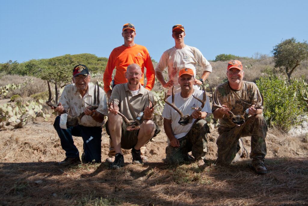 Conservancy hunting guides Kevin Ryan and Tyler Dvorak posing with four Wounded Warrior deer hunters on Catalina Island.